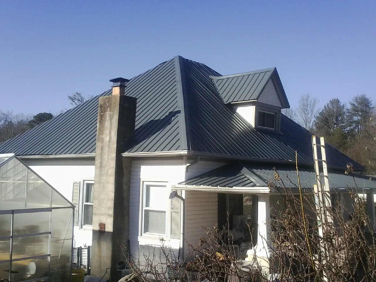 Dark blue standing seam metal roof on a white farmhouse with dormer — Slate & Tile Roof Repair by Roofing Brothers in Elko New Market