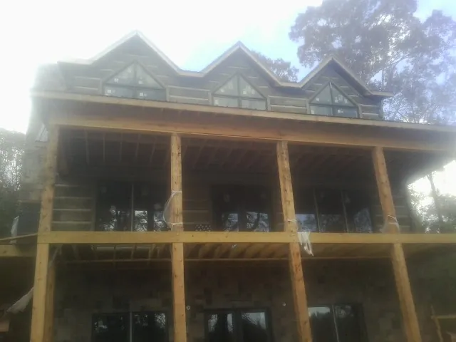 Dormers and porch framing on a large log home under construction — Roof Coating work by our crew in Elko New Market
