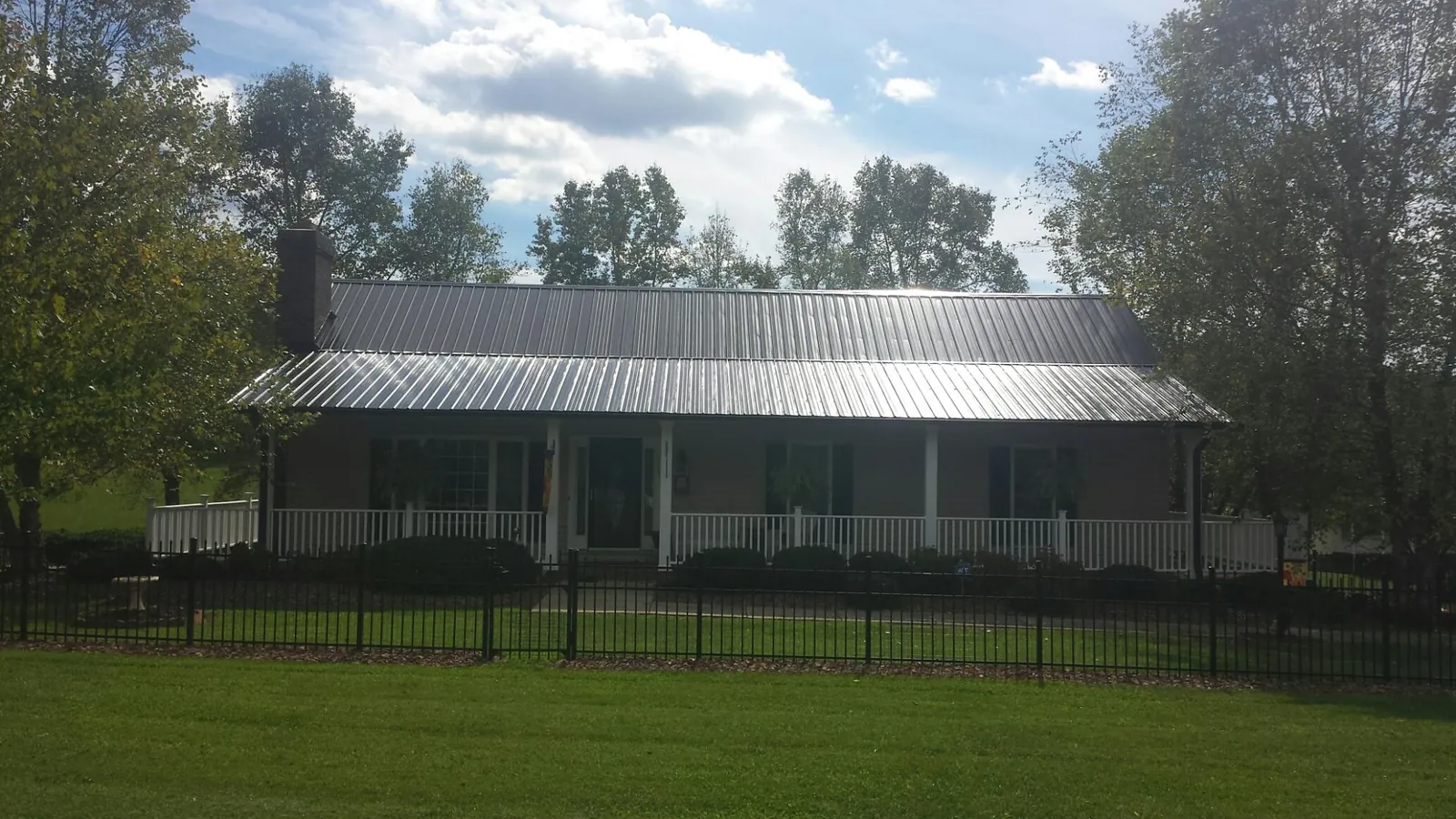 Gray metal roof on a brick ranch with a full width front porch — Gutter Guard Installation work by our crew in Elko New Market