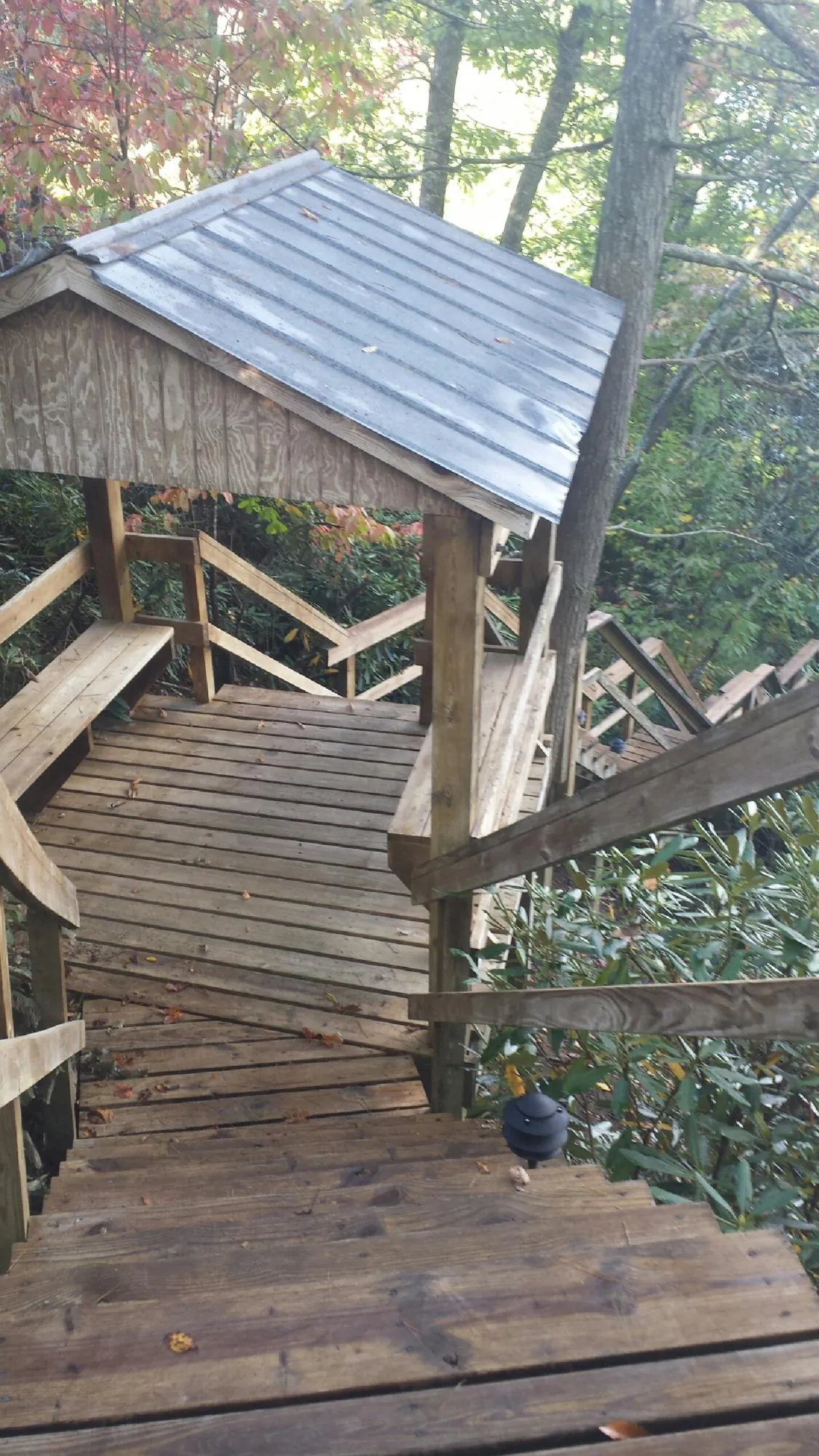 Metal roofed shelter over wooden steps on a wooded walkway — Skylight Repair & Installation work by our crew in Elko New Market