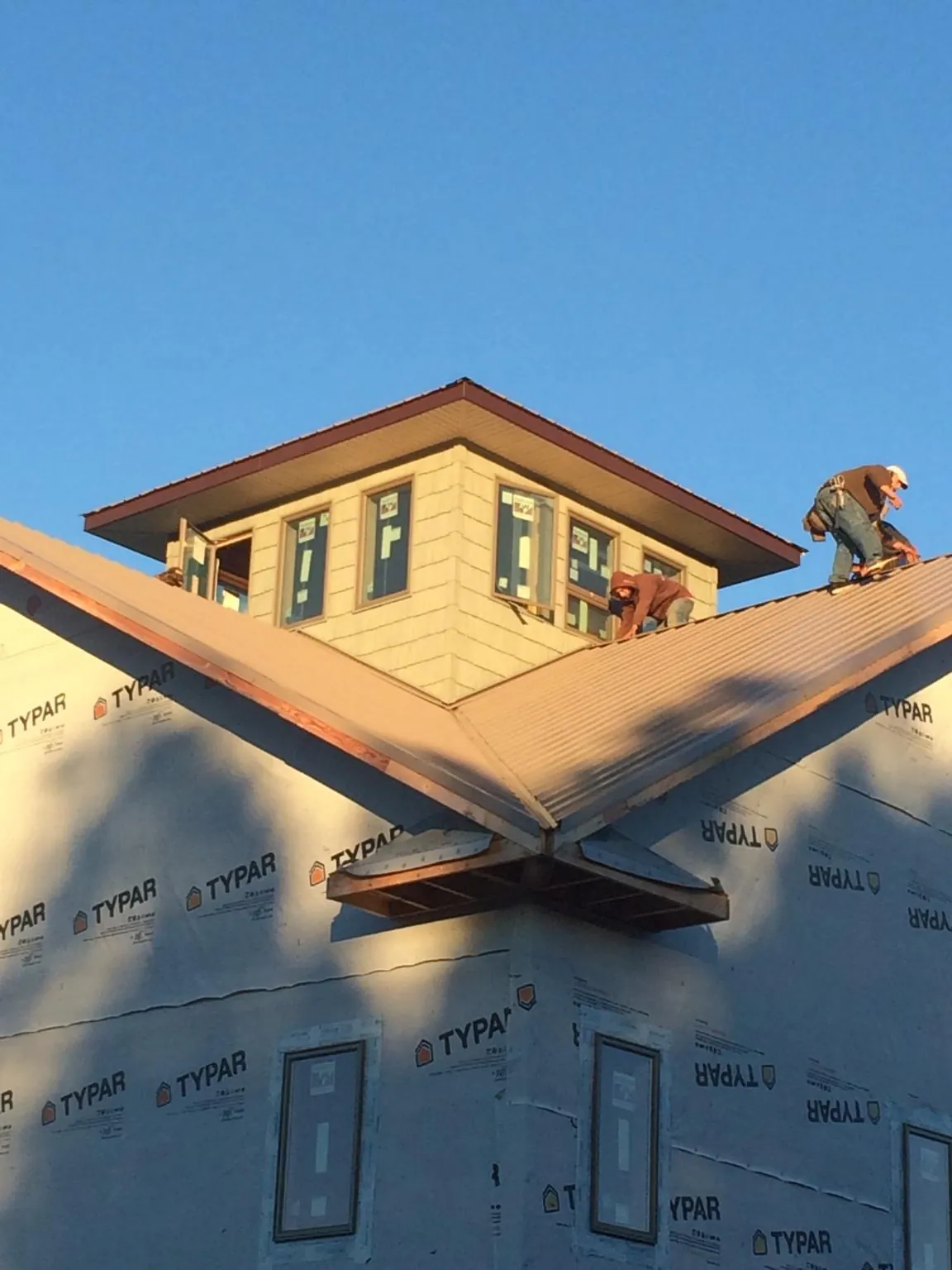 Roofers working around a rooftop cupola on a new metal roof at sunset — Roof Waterproofing in Elko New Market by Roofing Brothers
